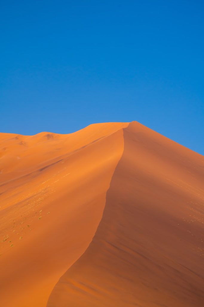 a large sand dune with a blue sky in the background